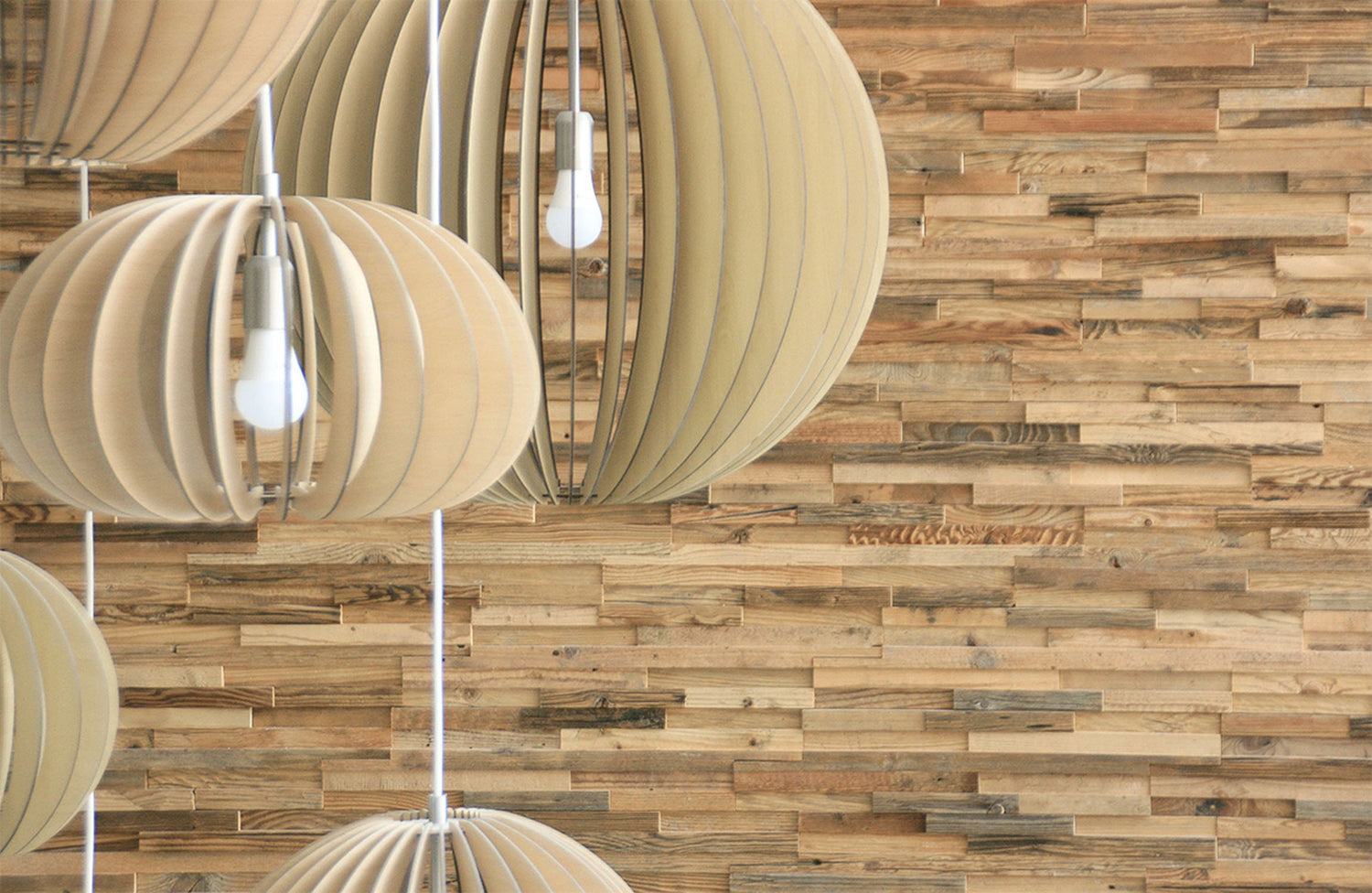Wooden pendant lights hanging against a wooden wall.